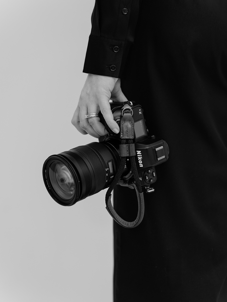 Lindsay Tiwald, NJ Brand and Interior Photographer, holds her Nikon Z8 mirrorless camera in her left hand. Photo is in black and white.